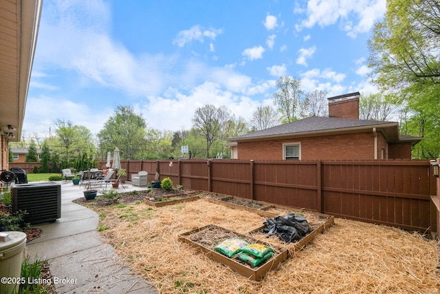 view of yard featuring a fenced backyard, a garden, central AC, and a patio