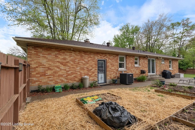 back of property with fence, a patio area, brick siding, and central AC unit