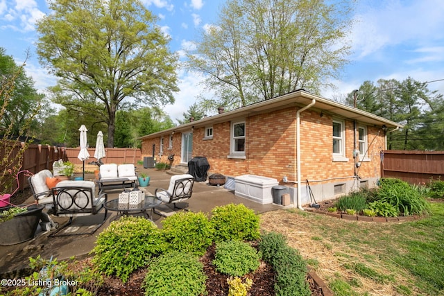 rear view of property featuring a fenced backyard, an outdoor hangout area, brick siding, and a patio
