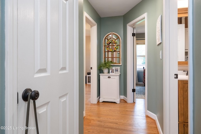 hallway featuring light wood-style flooring and baseboards