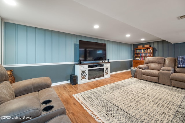 living area featuring baseboards, wood finished floors, recessed lighting, and ornamental molding