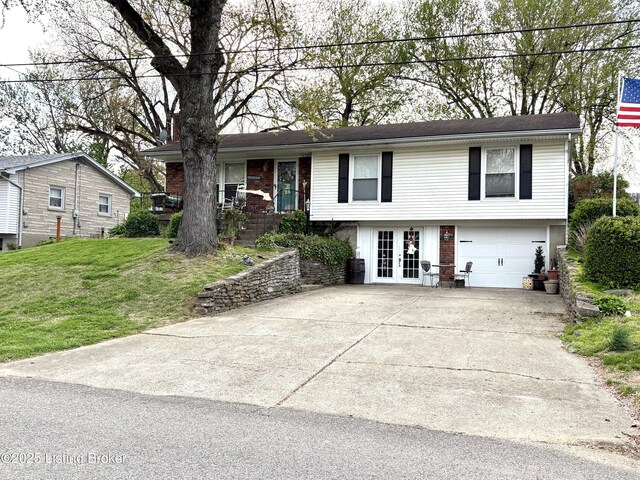 view of front of property with concrete driveway, a front lawn, french doors, and a garage