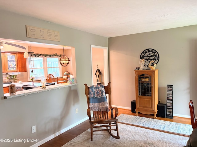 sitting room featuring baseboards, wood finished floors, and an inviting chandelier