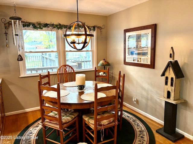 dining space with wood finished floors, baseboards, and an inviting chandelier