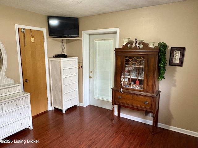 bedroom with dark wood finished floors and baseboards