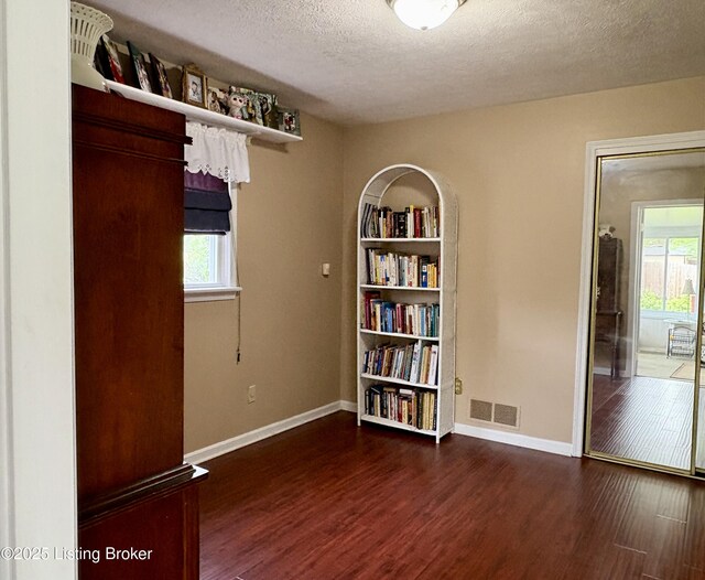 spare room with baseboards, visible vents, wood finished floors, and a textured ceiling