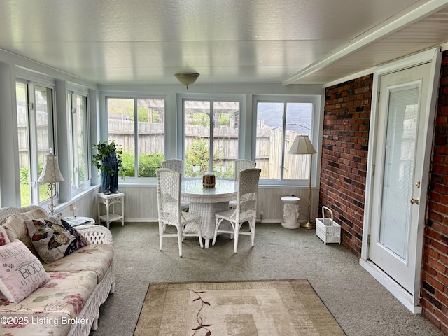sunroom with carpet floors and brick wall