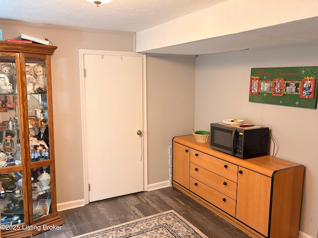 interior space featuring baseboards, a textured ceiling, dark wood-type flooring, and crown molding
