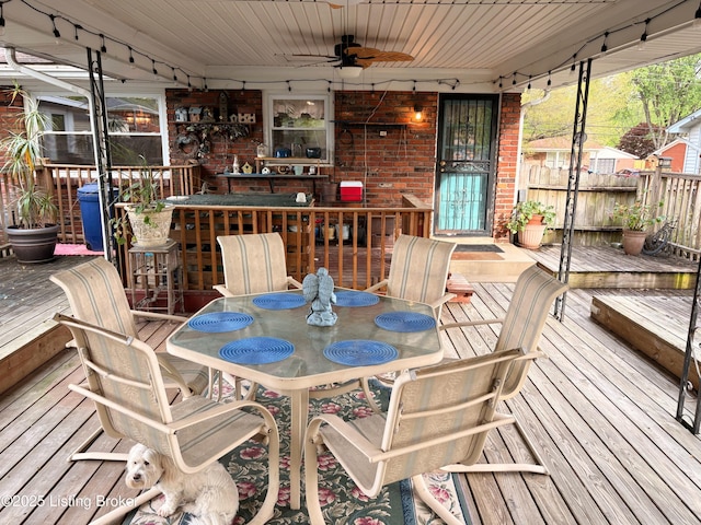 wooden terrace featuring fence, a ceiling fan, and outdoor dining space