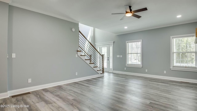unfurnished living room with ceiling fan, visible vents, stairs, and ornamental molding