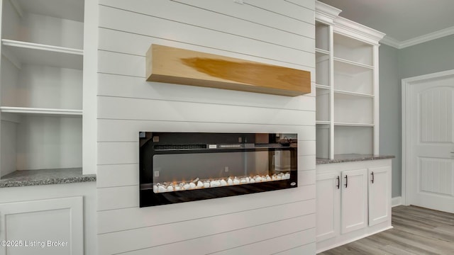 room details featuring crown molding, a glass covered fireplace, and wood finished floors
