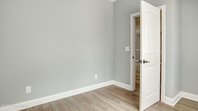 spare room with baseboards and light wood finished floors