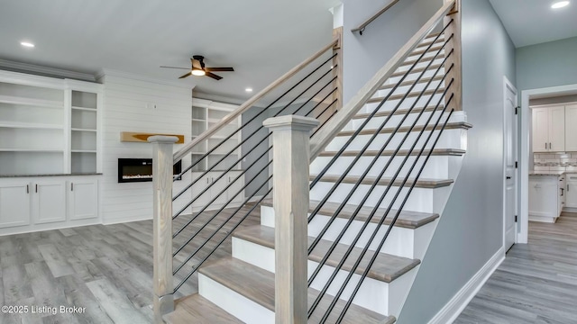 stairs with baseboards, recessed lighting, wood finished floors, ceiling fan, and a fireplace