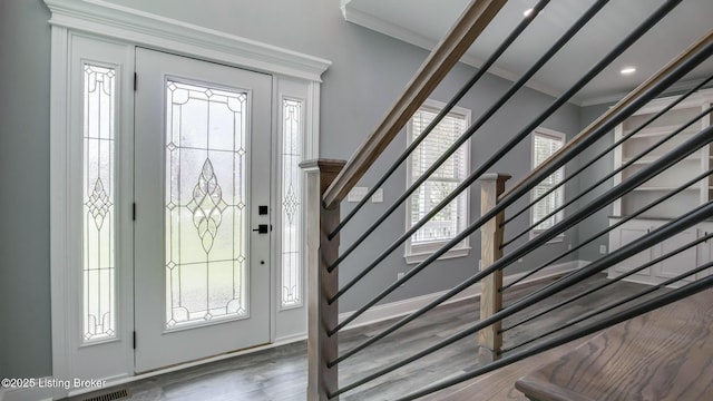entrance foyer with wood finished floors, stairs, and crown molding