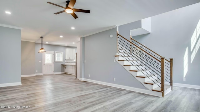 unfurnished living room featuring crown molding, stairs, light wood-type flooring, ceiling fan, and recessed lighting