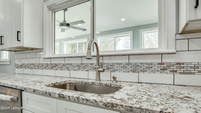 kitchen featuring white cabinets, backsplash, a ceiling fan, and a sink