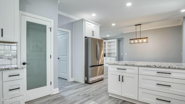 kitchen with white cabinets, recessed lighting, ornamental molding, and freestanding refrigerator