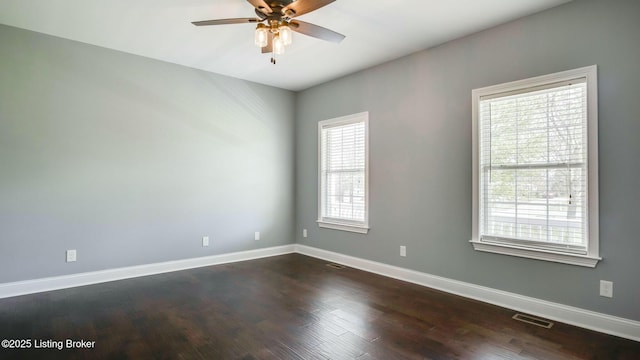 spare room featuring baseboards, visible vents, ceiling fan, and dark wood-style flooring