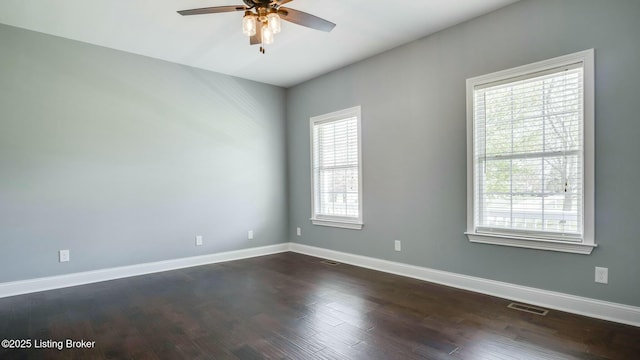 unfurnished room featuring baseboards, visible vents, dark wood-style floors, and ceiling fan