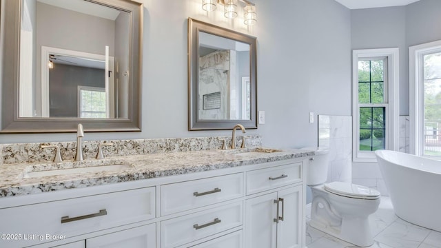 bathroom featuring a freestanding bath, double vanity, marble finish floor, and a sink