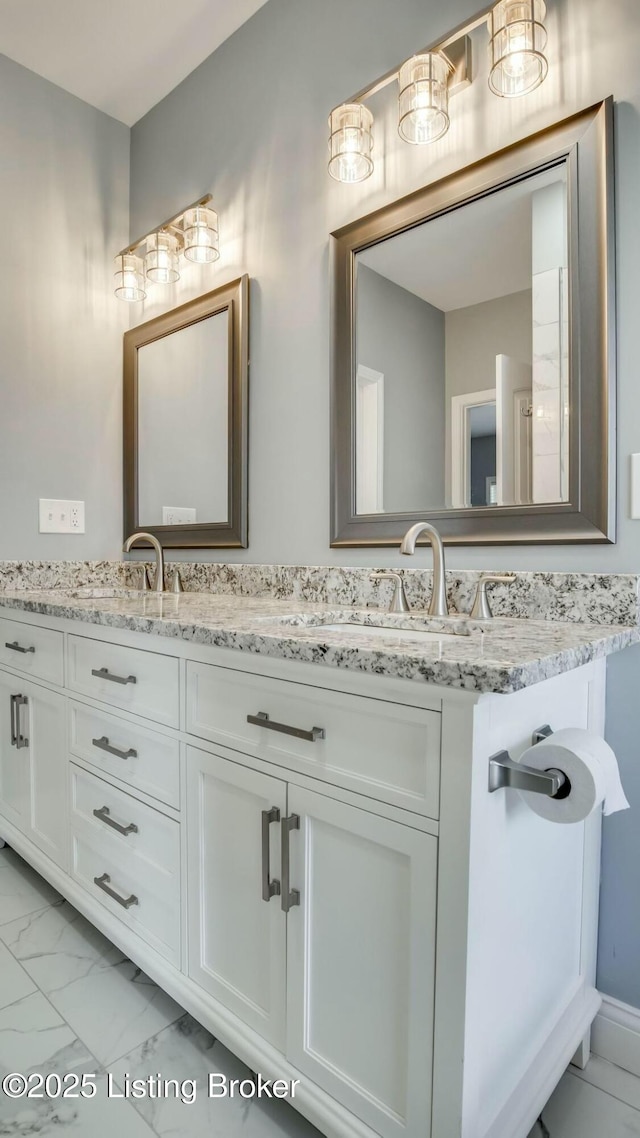 full bath featuring marble finish floor, a sink, and double vanity