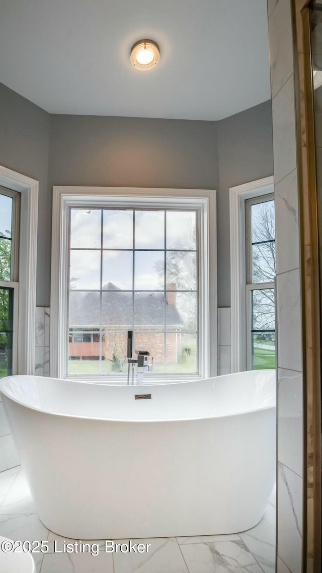 full bathroom featuring marble finish floor, a soaking tub, and plenty of natural light