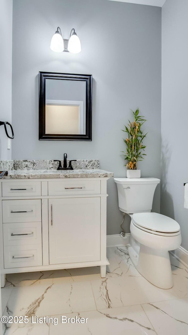 bathroom with marble finish floor, toilet, vanity, and baseboards