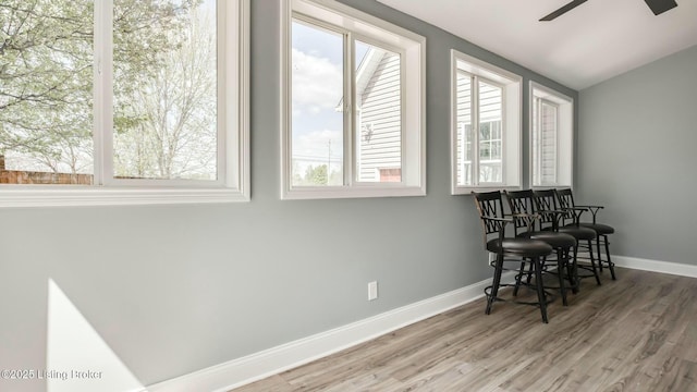 sitting room with baseboards, a ceiling fan, wood finished floors, and vaulted ceiling
