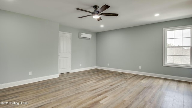 spare room featuring a wall mounted AC, wood finished floors, a ceiling fan, and baseboards