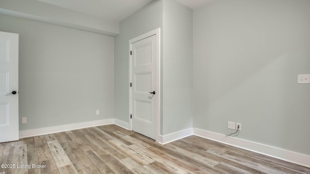 spare room featuring baseboards and light wood-style floors