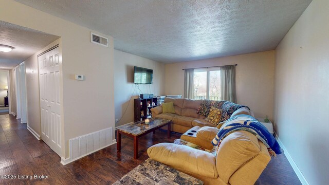 living area featuring wood finished floors, visible vents, and a textured ceiling