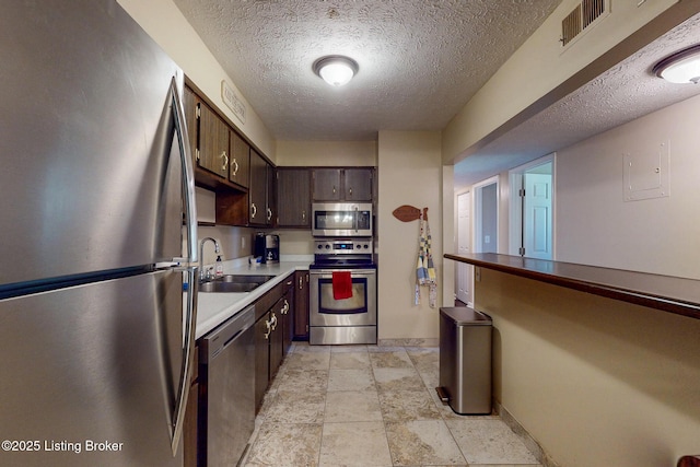 kitchen with visible vents, a sink, light countertops, dark brown cabinets, and stainless steel appliances