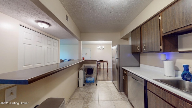 kitchen featuring dark brown cabinets, dishwasher, visible vents, a chandelier, and a textured ceiling