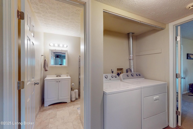 washroom featuring a textured ceiling, laundry area, a sink, and washer and clothes dryer