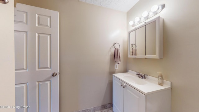 bathroom with baseboards, vanity, and a textured ceiling