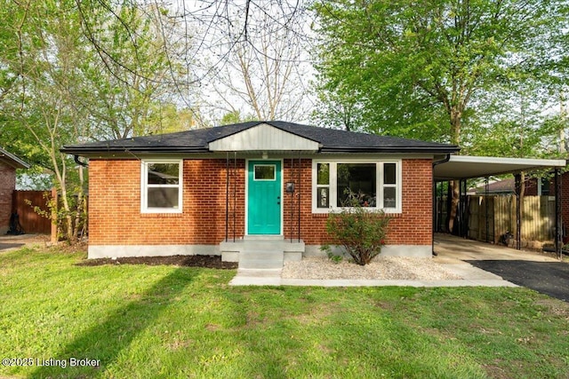 view of front of property featuring a front lawn, aphalt driveway, fence, an attached carport, and brick siding