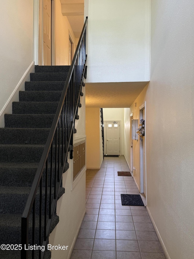 staircase with baseboards, tile patterned flooring, and a towering ceiling