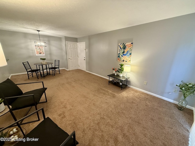 living area featuring baseboards, carpet flooring, and a chandelier