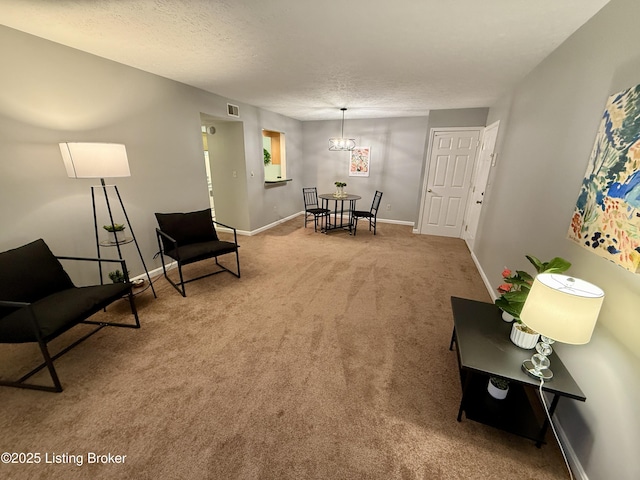 living area with a textured ceiling, visible vents, baseboards, an inviting chandelier, and carpet