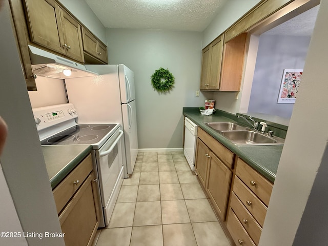 kitchen with dark countertops, a sink, under cabinet range hood, and white appliances