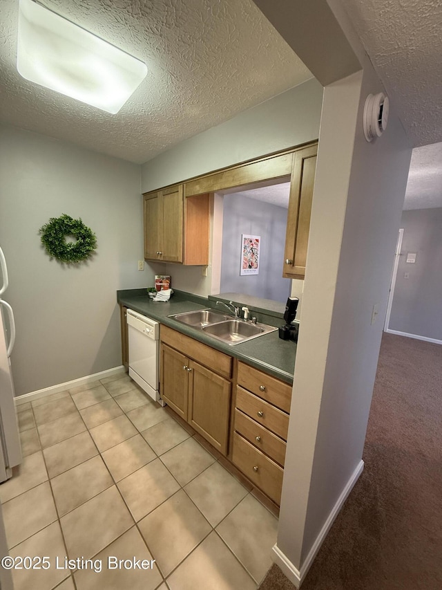kitchen featuring a textured ceiling, dark countertops, a sink, and dishwasher