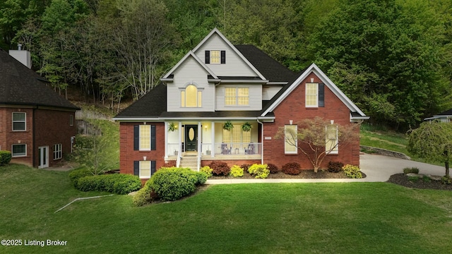 view of front of home with a front lawn, a porch, and brick siding