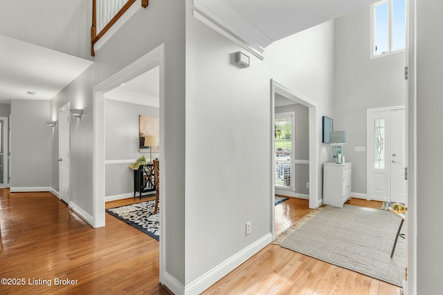 entrance foyer featuring ornamental molding, a high ceiling, wood finished floors, and baseboards