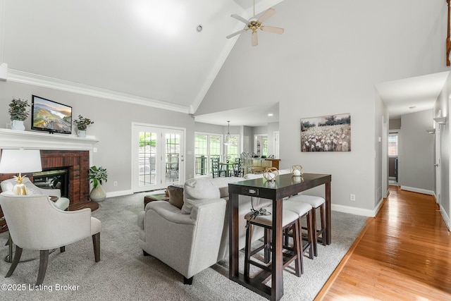 living room featuring baseboards, high vaulted ceiling, ornamental molding, and a healthy amount of sunlight