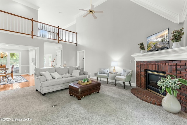living room with a brick fireplace, high vaulted ceiling, carpet floors, and baseboards