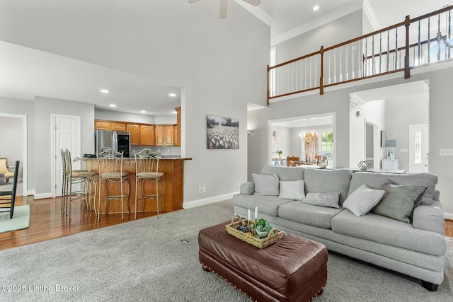 living area with ceiling fan, baseboards, recessed lighting, carpet, and a high ceiling
