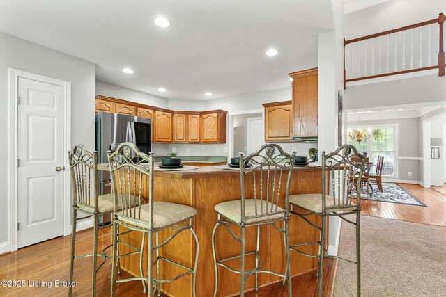 kitchen with a breakfast bar, recessed lighting, light wood-type flooring, and brown cabinetry