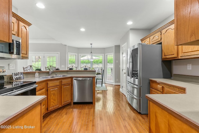 kitchen featuring a peninsula, a sink, brown cabinets, and stainless steel appliances