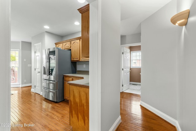 kitchen featuring light wood-style floors, light countertops, stainless steel fridge, and baseboards