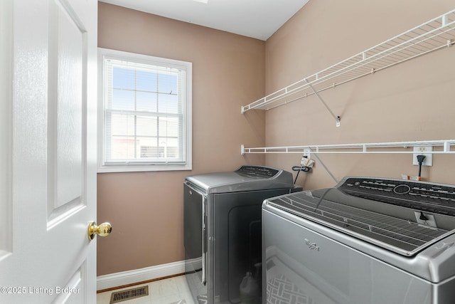 washroom featuring baseboards, visible vents, washer and clothes dryer, and laundry area